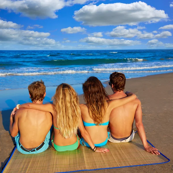 Amigos grupo casais sentados na praia areia traseira — Fotografia de Stock