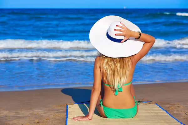 Jeune fille assise regardant la mer avec un chapeau de plage — Photo