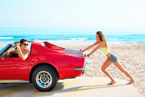 Дівчина штовхає зламану машину на пляжі смішний хлопець — стокове фото