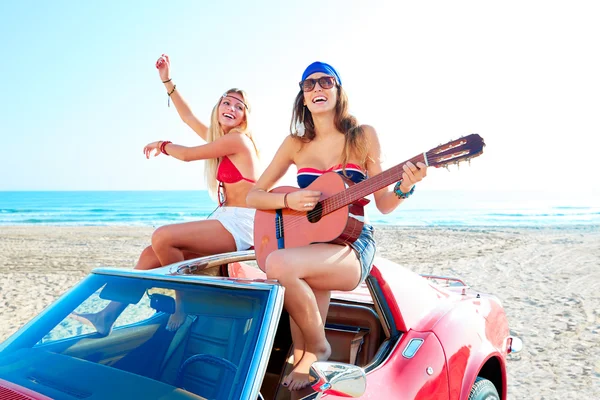 Τα κορίτσια διασκεδάζουν παίζοντας κιθάρα σε th παραλία σε ένα αυτοκίνητο — Φωτογραφία Αρχείου