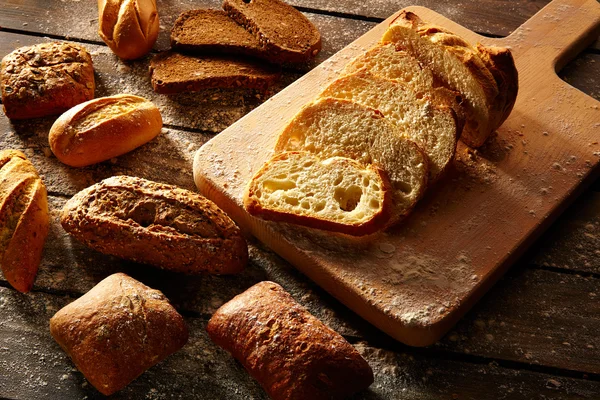 様々 なパン loafs で素朴な木の板をスライスしました。 — ストック写真