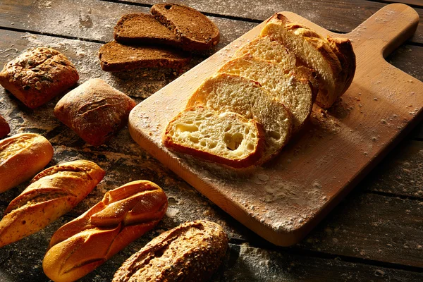 Brood gevarieerd loafs gesneden op een houten bord in rustieke — Stockfoto