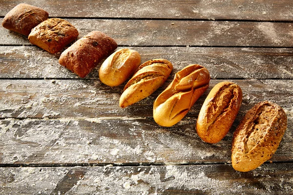 Pane varia di fila su legno rustico e farina — Foto Stock