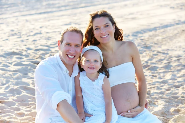 Семья с беременной матерью на пляже песка — стоковое фото