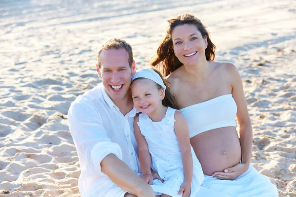 Rodina s těhotnou matku na pláž písek — Stock fotografie