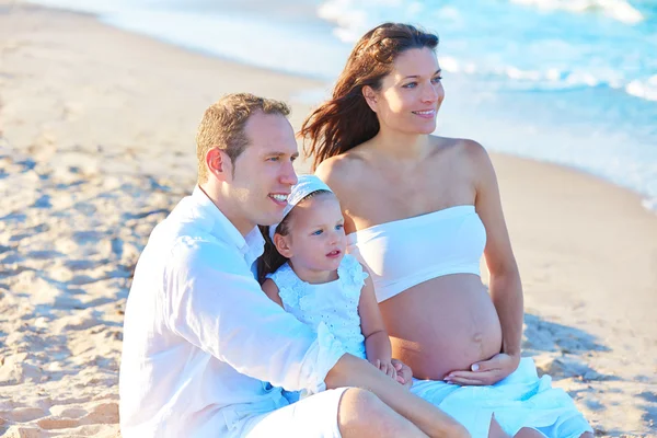 Сім'я з вагітною матір'ю на пляжному піску — стокове фото