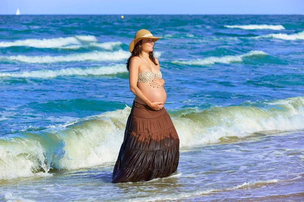 Těhotná žena na pláži s vlnami — Stock fotografie