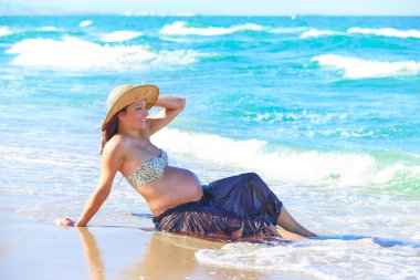 Dalgalar ile sahilde hamile kadın