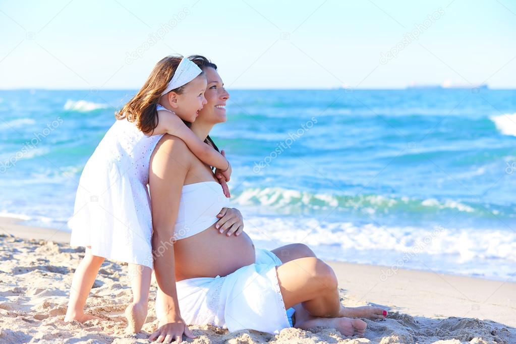Pregnant mother and daughter on the beach
