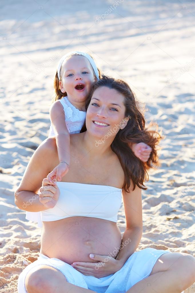 Pregnant mother and daughter on the beach