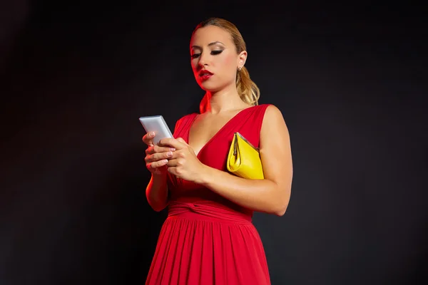 Блондинка в красном написании смартфона — стоковое фото