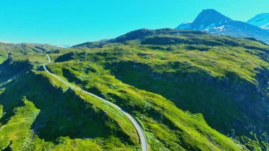 Turtagro Turtagro 'nun dolambaçlı dağ yolu, çayırlar ve kar zirveleri manzarası
