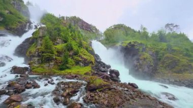 Güçlü Latefossen şelalesi Parlak bir yaz gününde Norveç 'teki taş köprü arkasında.