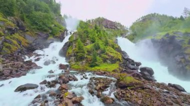 Güçlü Latefossen şelalesi Parlak bir yaz gününde Norveç 'teki taş köprü arkasında.