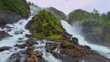 Güçlü Latefossen şelalesi Parlak bir yaz gününde Norveç 'teki taş köprü arkasında.