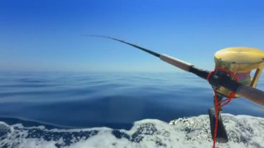 Deniz aşırı balıkçı teknesinde olta, açık deniz dalgası ve açık gökyüzünün altında mavi su.