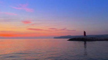 San Antonio Burnu üzerinde Denia gün doğumu, sakin deniz, renkli gökyüzü, deniz feneri ve tekne Costa Blanca 'da, Marina Alta