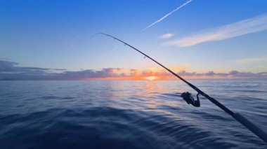 Gün batımında açık denizde balık tutmak, sakin denizde olta atmak, mürekkep balığı ve kaya türleri için altın ufuk.