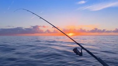 Gün batımında açık denizde balık tutmak, sakin denizde olta atmak, mürekkep balığı ve kaya türleri için altın ufuk.