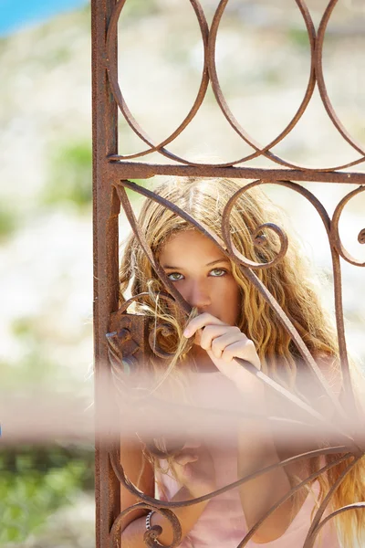 Blond girl in Mediterranean rusted gate at sea — Stock Photo, Image