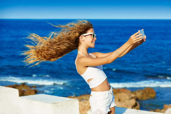 สาววัยรุ่นผมบลอนด์ถ่ายรูปเซลฟี่บนสมาร์ทโฟนที่ชายหาด — ภาพถ่ายสต็อก