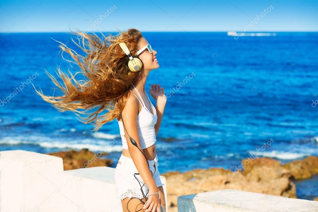 Blond kid teen girl headphones music on the beach