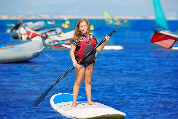Kind paddle surf surfer girl mit ruder im strand — Stockfoto