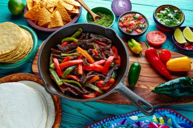 Beef fajitas in a pan sauces chili and sides Mexican clipart