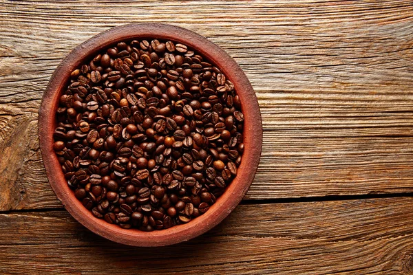 Granos de café en un plato de arcilla textura en madera —  Fotos de Stock