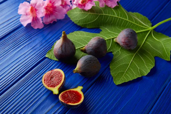 Figues fruits coupés crus et feuilles de figuier sur bleu — Photo
