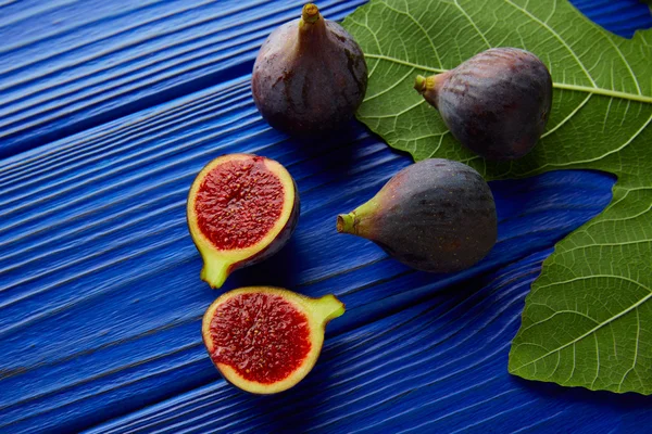 Higos cortados crudos frutas y hojas de higuera en azul —  Fotos de Stock