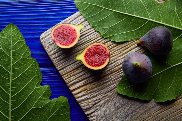 Figs raw cutted fruits and fig tree leaves on blue — Stock Photo, Image