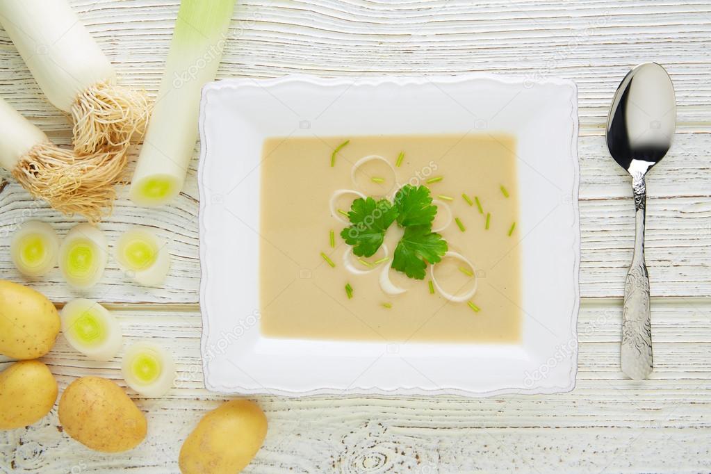vichyssoise cream soup with leeks on white wood