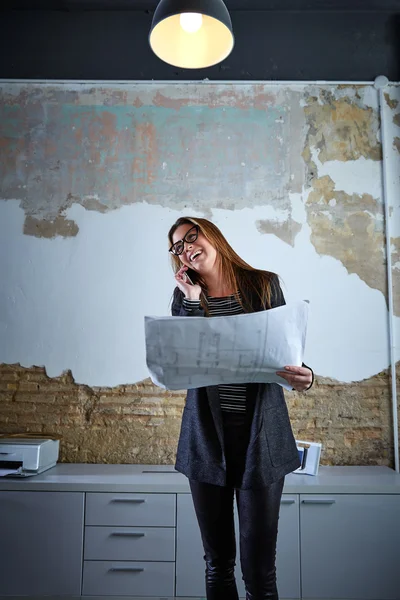 Architekt kobieta rozmowy telefon trzymając papier plan — Zdjęcie stockowe