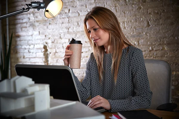 Бізнес-леді п'є каву, працюючи в офісі — стокове фото