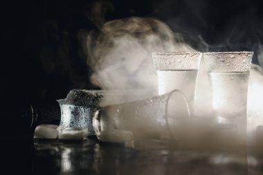 Siyah buzun üzerinde duran votka şişesinin yakın plan görüntüsü.