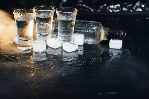 Detailní Pohled Láhev Vodky Brýlemi Stojícími Ledu Černé — Stock fotografie