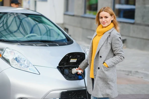 Woman charging electro car at the electric gas station