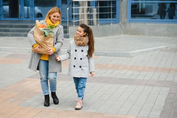 家庭购物 妈妈和她的女儿在商店附近拿着装有蔬菜的购物袋 — 图库照片