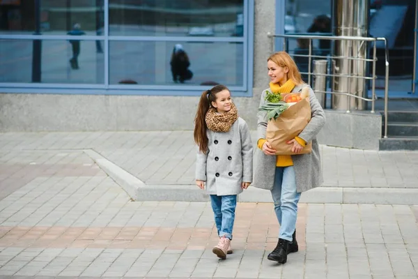 家庭购物 妈妈和她的女儿拿着装有蔬菜的购物袋 — 图库照片