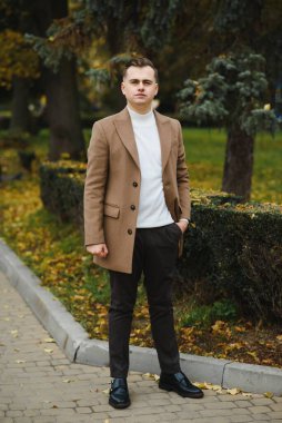 Palto giymiş, açık havada sakallı şık bir adamın portresi.