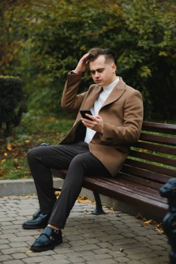 Palto giymiş, açık havada sakallı şık bir adamın portresi.