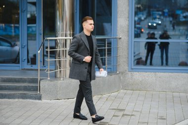 Sokakta evrak okuyan ciddi bir iş adamı. Evrakları dışarıda inceleyen kendine güvenen bir iş adamı. Şehir caddesinde belgelerle dolaşan düşünceli bir adam..