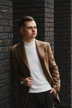 1920 'lerde Peaky at gözlüğü takmış eski tuğla duvarın yanında eski bir İngiliz gangsteri gibi poz veren bir adam..