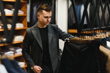 Müşteri, elbise ceketinin fiyatına bakan şık bir adam. Klasik bir kostüm mağazasında, askıda..