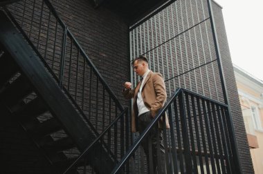 Palto giymiş, açık havada sakallı şık bir adamın portresi.