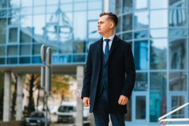 Yüksek moda görünüşlü. Genç stil sahibi, kendine güvenen, takım elbiseli, sokakta yürüyen yakışıklı iş adamı modeli..