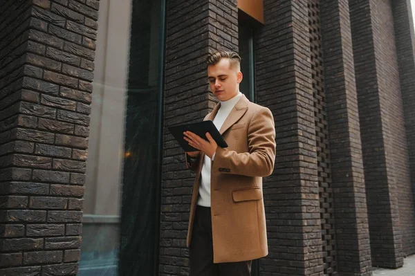 Palto giymiş, açık havada sakallı şık bir adamın portresi.