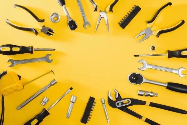 Yellow and black handy tools (pilers and screwdriver) isolated on yellow background