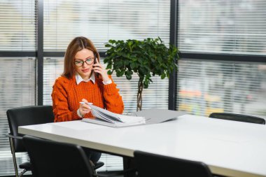 Ofisteki masada otururken cep telefonunda yazan mutlu bayanın portresi.